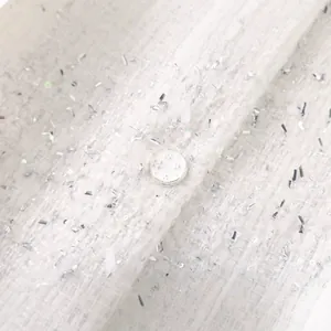 Détail du tissu en tweed blanc tissé avec des paillettes argentées et bouton
