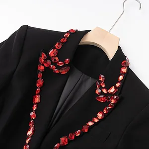 Detail of black blazer lapels featuring sparkling red crystal bead embellishments for parties.