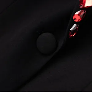 Close-up of luxury black blazer with red bead embellishments and fabric button.