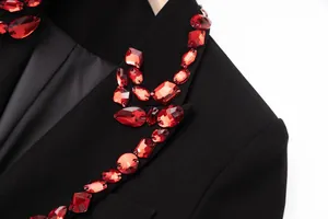 Macro detail of luxury red jewel embellishments on a black women's blazer lapel