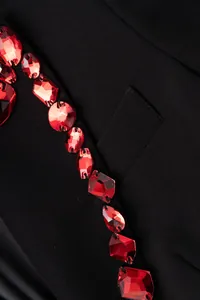 Close-up detail of luxury black blazer with faceted red gemstone embellishments