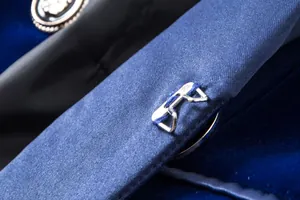 Detailed view of navy blue velvet blazer featuring a silver metal hook closure and shawl collar.