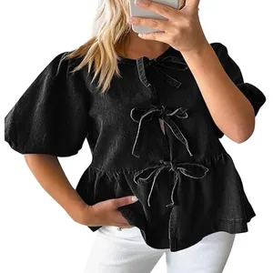 Dettaglio camicia in denim nero da donna con tre chiusure a fiocco sul davanti.