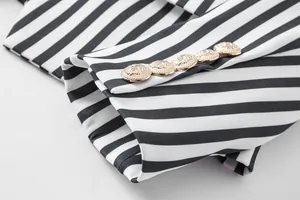 Detalle del puño de un blazer a rayas con botones dorados de cabeza de león tallada