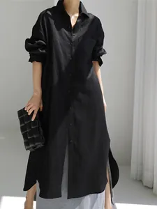 Vista detallada del vestido camisero largo de lino negro con un dobladillo irregular.