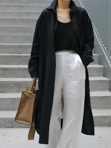 Detalle de un cárdigan largo de algodón y lino negro sobre pantalones anchos blancos brillantes