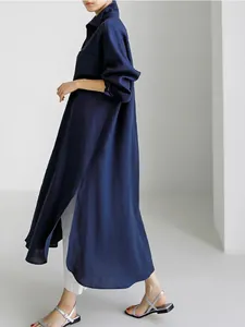 Detalle de un vestido camisero largo y suelto de algodón y lino azul con aberturas