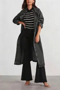 Full body view showing the styling and loose fit of the long black denim trench coat
