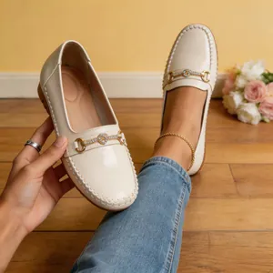 Mocasines de charol beige con detalle de bocado dorado y cristales en primer plano