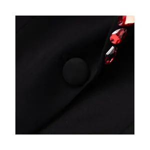Close-up detail of luxury black blazer featuring red gemstone beads and fabric covered button