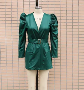 Detailansicht eines eleganten grünen PU-Lederkleides mit modischen Puffärmeln und Gürtel.
