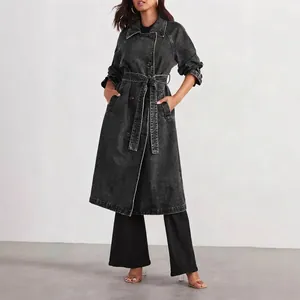 Women's long black denim trench coat featuring a waist belt and contrast stitching.