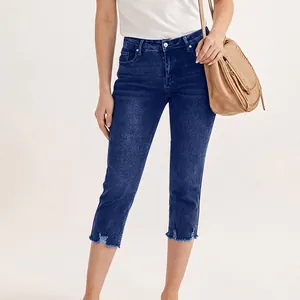 Modèle portant un pantalon capri en denim bleu foncé extensible sur fond blanc neutre