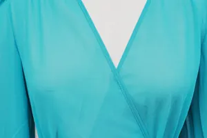 Close-up detail of the elegant V-neckline and sheer turquoise chiffon fabric of the dress.