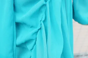 Macro detail of turquoise chiffon fabric showing delicate texture and soft pleats