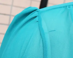 Close-up detail of the lightweight teal chiffon fabric and fine pleated stitching on a dress