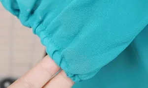 Macro detail of turquoise chiffon dress sleeve showing elastic smocked cuff and fabric.