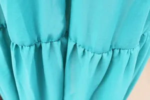 Detailed macro view showing the pleated stitching on a vibrant cyan chiffon beach dress.