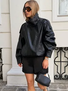 Detailansicht einer stylischen schwarzen Oversize-PU-Leder-Bikerjacke in urbaner Umgebung.