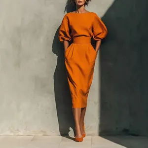 Vue détaillée d'un ensemble orange avec haut à manches bouffantes et jupe midi plissée chic.