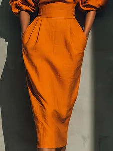 Gros plan de la jupe midi plissée orange à taille haute et détails de tissu texturé.