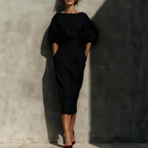 Ensemble chic noir avec haut à col bateau, manches bouffantes et jupe midi plissée