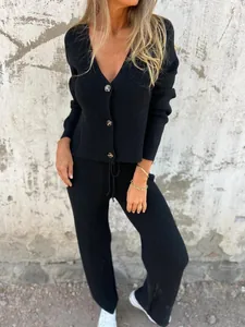 Detalle del conjunto de cárdigan de punto negro y pantalones con cordón y cuello en V