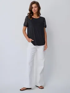 T-shirt nera elegante con maniche in pizzo e pantaloni bianchi a gamba larga su modella