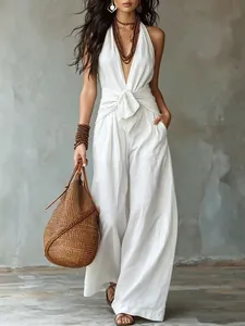 Detail van een witte mouwloze jumpsuit met halternek, striktaille en wijde pijpen.
