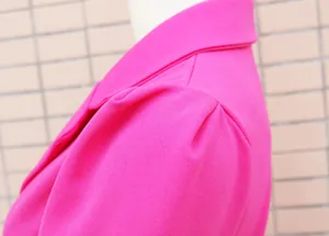 Dettaglio in primo piano della manica a sbuffo magenta e del rever di un abito blazer sottile.