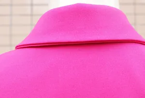 Dettaglio ravvicinato del rever di un abito blazer rosa magenta con trama del tessuto