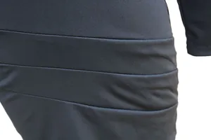 Dettaglio macro della trama del tessuto nero arricciato su un abito da sera aderente.
