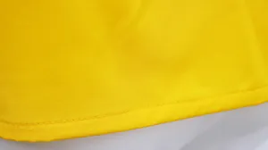Macro view of the fine stitching on the hem of a yellow casual women's vest top.