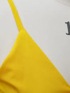 Macro shot of bright yellow camisole top strap and fabric texture on white mannequin