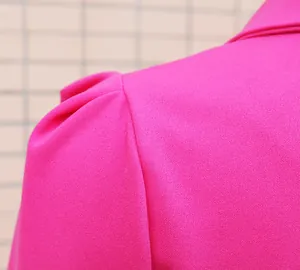 Dettaglio del design della spalla con manica a sbuffo su abito blazer fucsia aderente