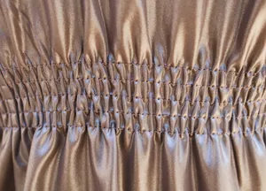 Detailansicht der gesmokten elastischen Taille eines braunen Trenchcoats aus Kunstleder.