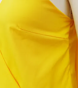 Close-up of yellow fabric texture and neat stitching on a V-neck summer camisole