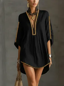 Detail of black vacation dress with gold Western ribbon trim and textured fabric