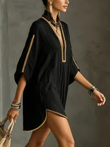Close-up detail of black bohemian vacation dress with golden western webbing trim decor