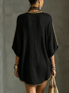 Detailed back view of a black textured resort dress with elegant gold braid trim