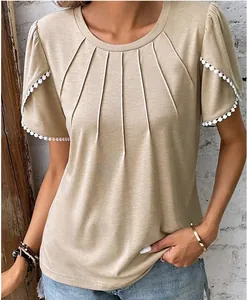 Detail of the pleated neckline and tulip sleeves with pom-pom trim on khaki T-shirt