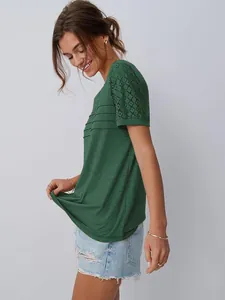 Dettaglio t-shirt verde con maniche in pizzo traforato e pieghe frontali.
