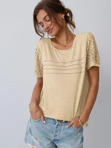 Dettaglio delle maniche in pizzo traforato e pieghe sul petto della t-shirt gialla da donna
