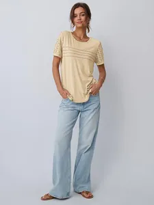 Dettaglio di una maglietta beige ampia con eleganti maniche in pizzo e girocollo.