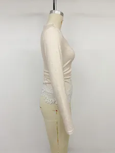 Side detail of a slim-fit knit top featuring elegant white lace hem patchwork.