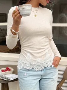 Close-up of beige knitted long-sleeve top featuring delicate white lace trim detail