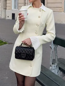 Detail view of a cream tweed blazer dress featuring pleated cuffs and gold buttons.