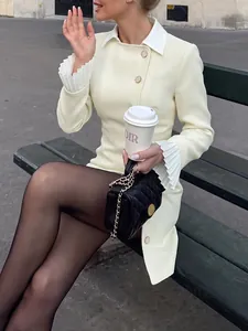 Close-up of cream blazer dress featuring pleated flare sleeves and gold buttons.