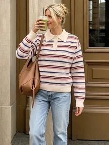 Pull rayé à col polo élégant pour femme porté par un mannequin dans un cadre urbain.