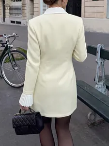 Elegant cream tweed fake two-piece blazer dress with white pleated cuffs in street view.